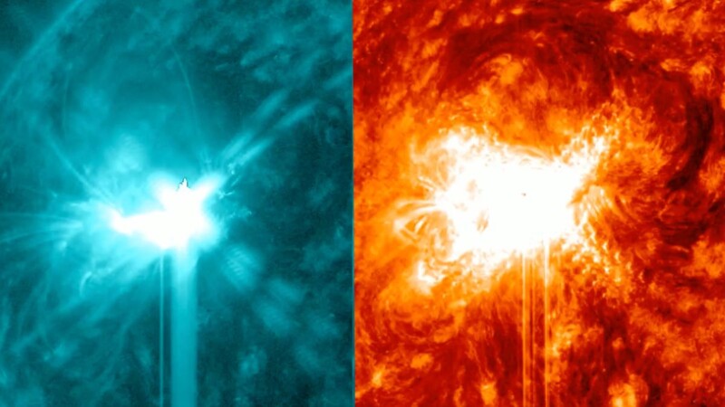 An image shows a large solar flare in teal and orange. 