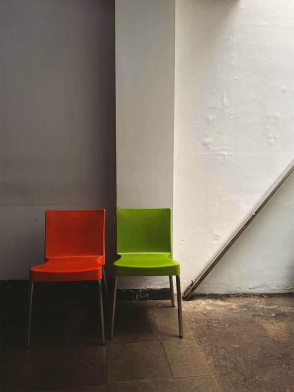 Sony World Photography Awards 2024 Open competition category winners -- object, two chairs against a white wall. One chair is red, the other is green. Abstract patterns of shadow.