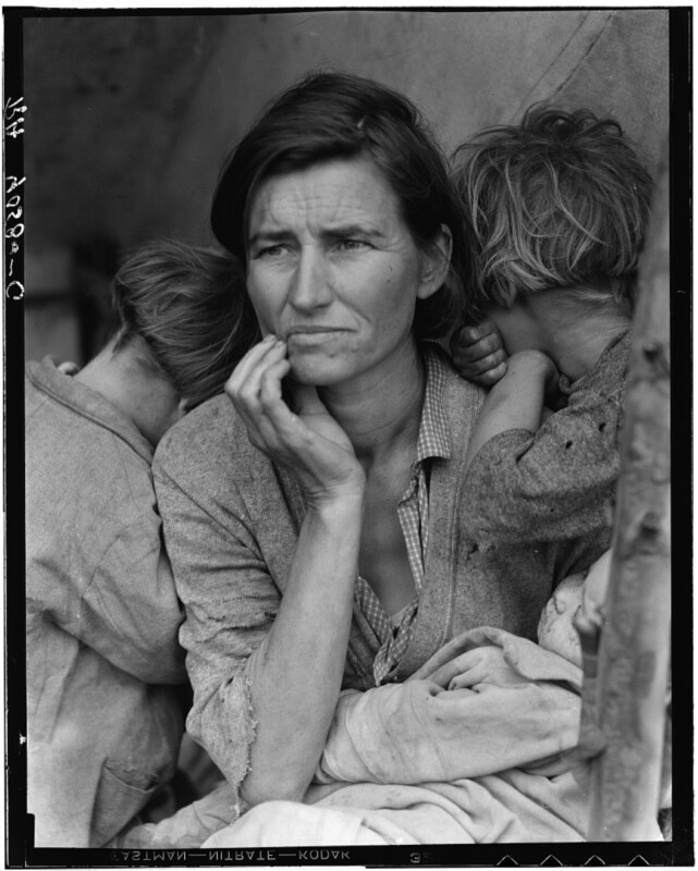 A woman sits with a concerned look while two young children lean on her, facing away from the camera.