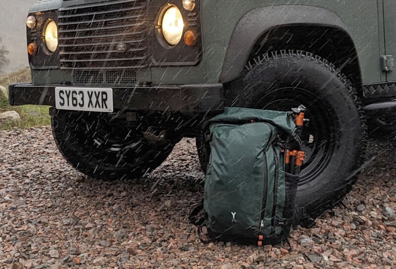 The Fjord 50-C camera backpack rests on the ground by a car.