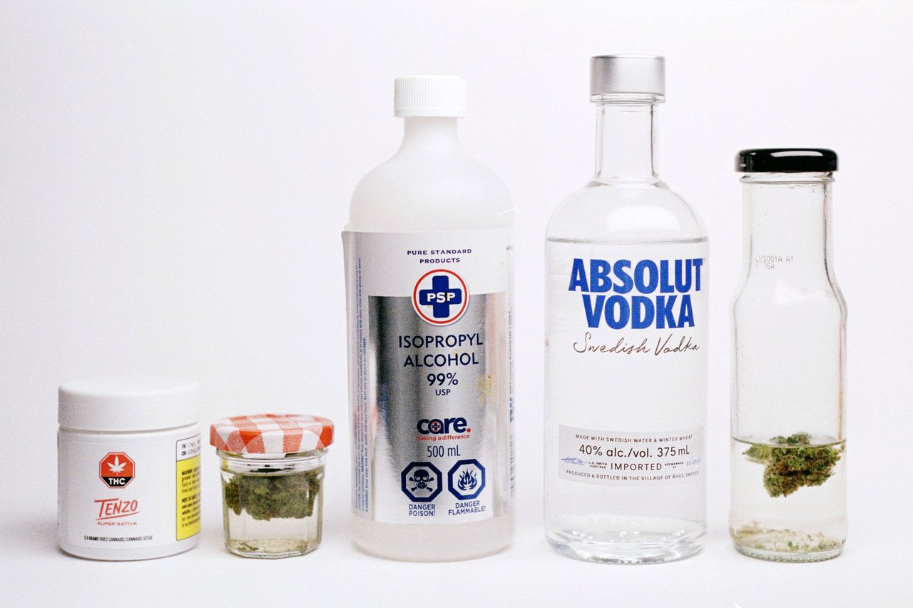 A lineup of various bottles and containers on a white background, including a jar of tenzo tea, a psp isopropyl alcohol bottle, a bottle of absolut vodka, and a glass jar with dried herbs.