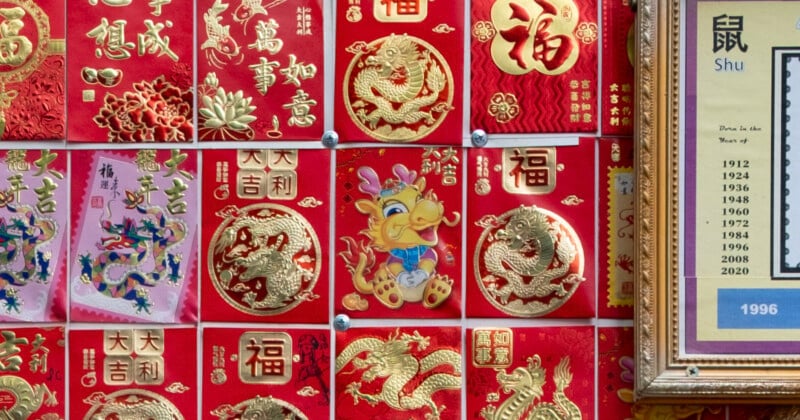A display of colorful chinese new year cards adorned with dragons, phoenixes, and traditional symbols, next to a zodiac calendar for the "year of the rat.