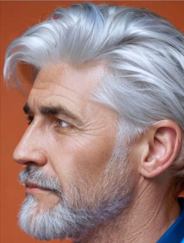 Profile view of an older man with distinguished silver hair and beard, showing detailed facial features against a soft orange background.