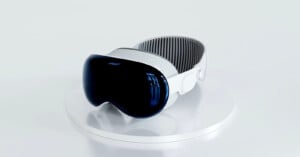 A sleek, modern virtual reality headset with a white and black design, featuring a glossy curved visor, displayed on a white pedestal against a light gray background.