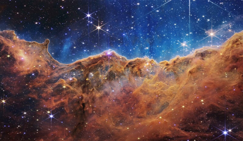 A vibrant image of a cosmic region with glowing stars and intricate clouds of gas and dust in brilliant shades of orange and gold, evoking a sense of depth and vastness in the universe.