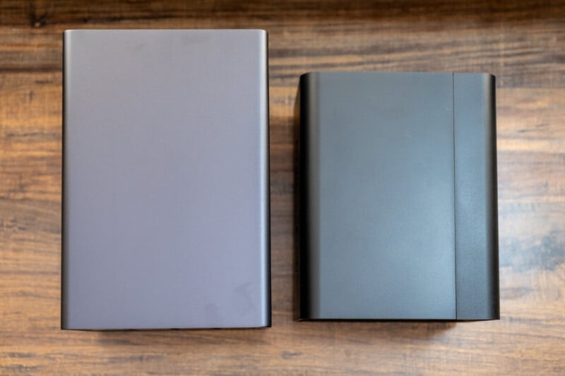 Two closed laptops, one with a smooth finish and the other with a textured cover, lying side by side on a wooden tabletop.