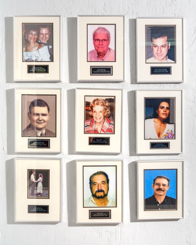 A collection of nine framed photographs on a white wall, featuring portraits of diverse people, each with an accompanying nameplate.