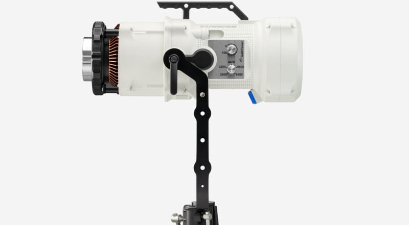Side view of a professional white cinema camera mounted on a rig with visible adjustment knobs and components, isolated on a gray background.