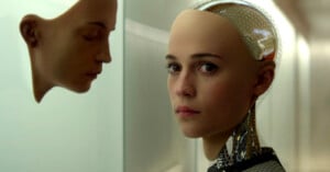 A woman with a bald head and futuristic attire stands beside a highly realistic humanoid robot that mirrors her appearance, highlighting a stark contrast in human and ai aesthetics.