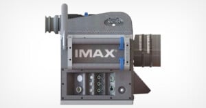 A digital render of an imax film projector featuring intricate details including reels, lenses, and a "max" label on a textured gray body.