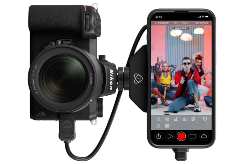 A nikon camera connected by a cable to an iphone displaying a live video shoot of two stylized people posing, with the screen showing filming controls and battery status.