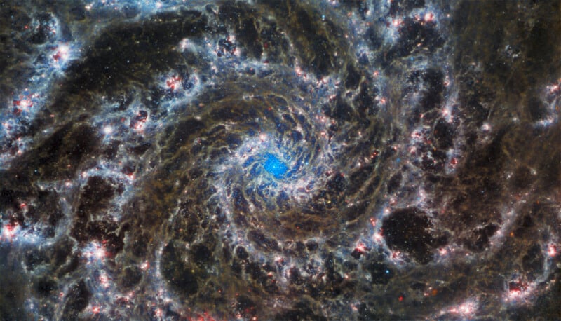 A highly detailed view of a galaxy with intricate spirals of stars and cosmic dust, predominately in hues of blue and white, set against a dark, starry background.