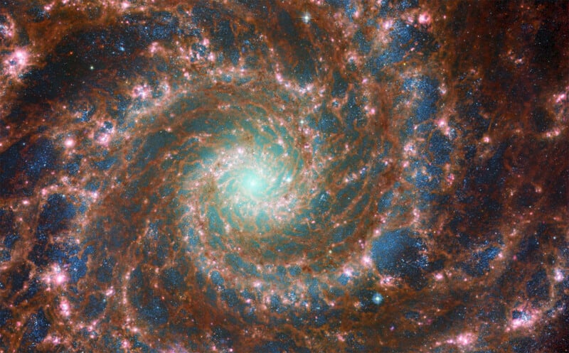 A detailed image of a spiral galaxy with numerous stars and swirling cosmic dust in various shades of blue and brown, centered around a bright, glowing core.
