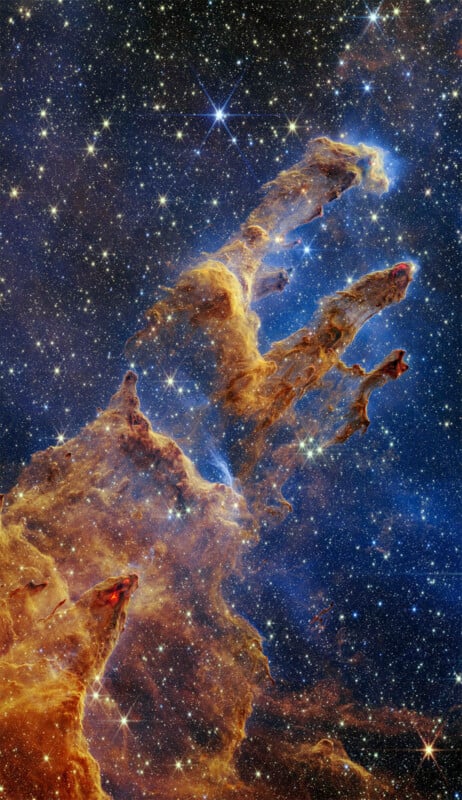 A vibrant image of the pillars of creation in space, depicting tall columns of interstellar gas and dust against a backdrop of glittering stars.