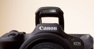 Close-up of a canon eos camera focusing on the brand name and model, with a soft beige background.