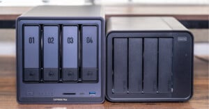 Two multi-bay hard drive enclosures on a wooden surface, with visible labels and ports, used for data storage and backup.