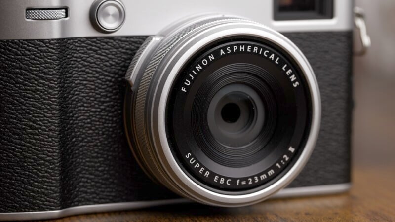 Close-up of a vintage-style fujifilm camera focusing on the textured details and markings on the lens and body.