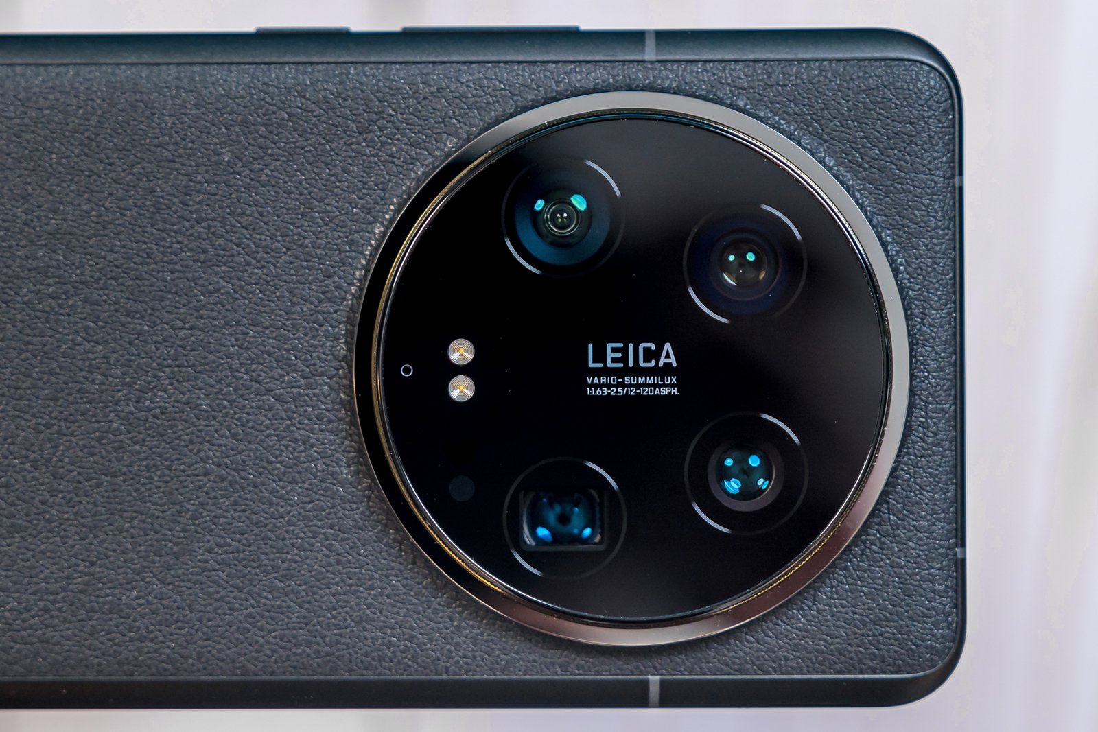 Close-up of a smartphone's black rear camera module branded by leica, featuring four lenses arranged symmetrically, with a flash and sensor visible.