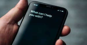 A Siri prompt on an iPhone asks, "What can I help you with?"