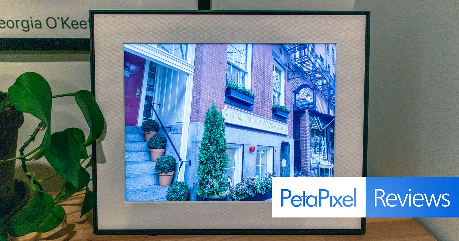 A digital frame displaying a photo of a quaint blue building with a sign labeled 