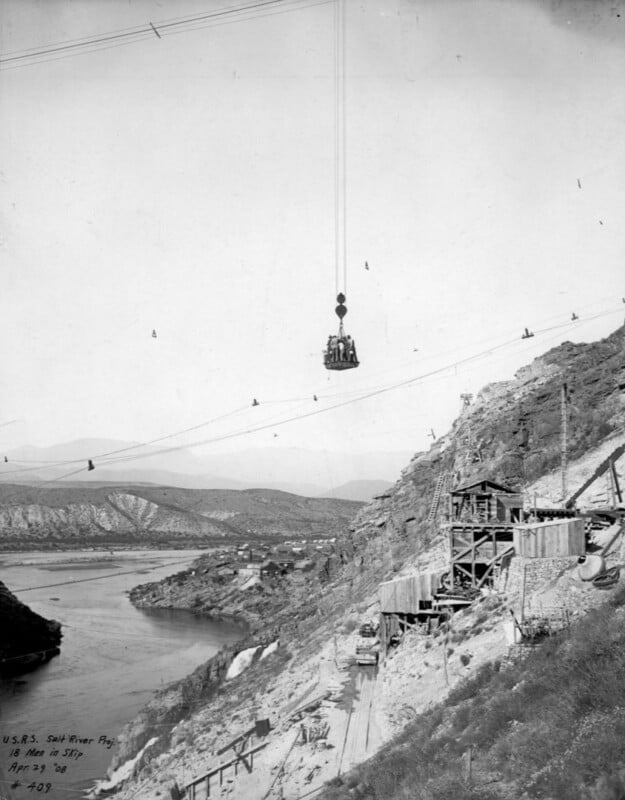 18 men ride a skip cable car in 1908.