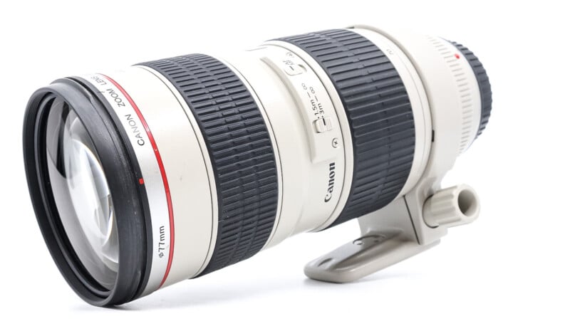 White canon EF 70-200mm f/2.8L IS USM telephoto lens isolated on a plain background, showing detail of zoom ring, focus switches, and tripod mount.