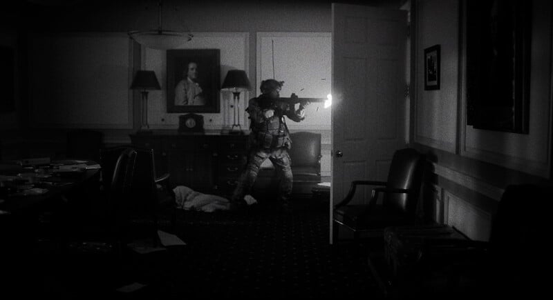 A soldier in camouflage gear cautiously moves through a dimly lit room, aiming a rifle with an attached flashlight, amidst scattered papers and overturned furniture.