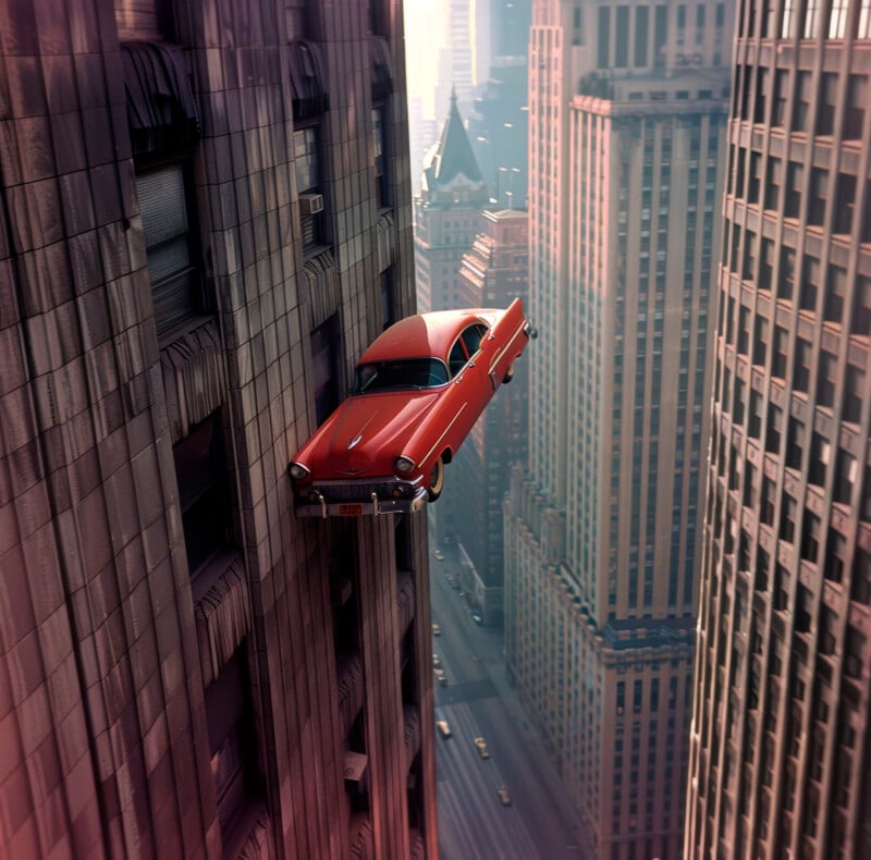A red vintage car dramatically flies out of a skyscraper window, hovering over an urban canyon with dense, sunlit high-rise buildings.