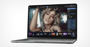 A laptop displaying a photo editing software with a glamorous portrait of a woman with curly blonde hair and colorful makeup on the screen. the software interface shows various editing tools and options.