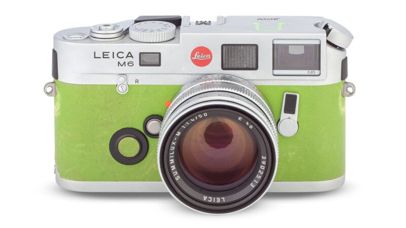 A Leica M6 film camera with a bright green leather covering and a silver metal body, featuring a large lens and detailed dials and controls on the top.