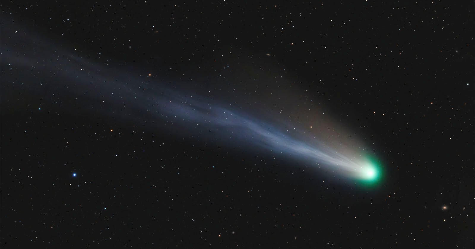 A vivid image of a bright comet with a glowing nucleus and a long, flowing tail traveling through a star-studded night sky.