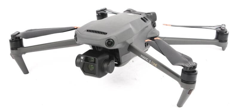 A gray DJI quadcopter drone with extended arms and propellers, featuring a camera mounted on the front. the drone is positioned on a plain white background.