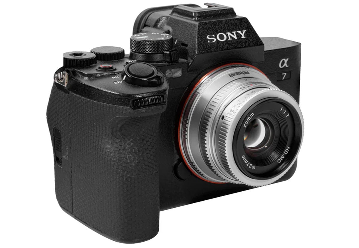 A sony alpha 7 mirrorless camera with a silver and black vintage-style lens attached, focused on the lens and control dials, on a white background.