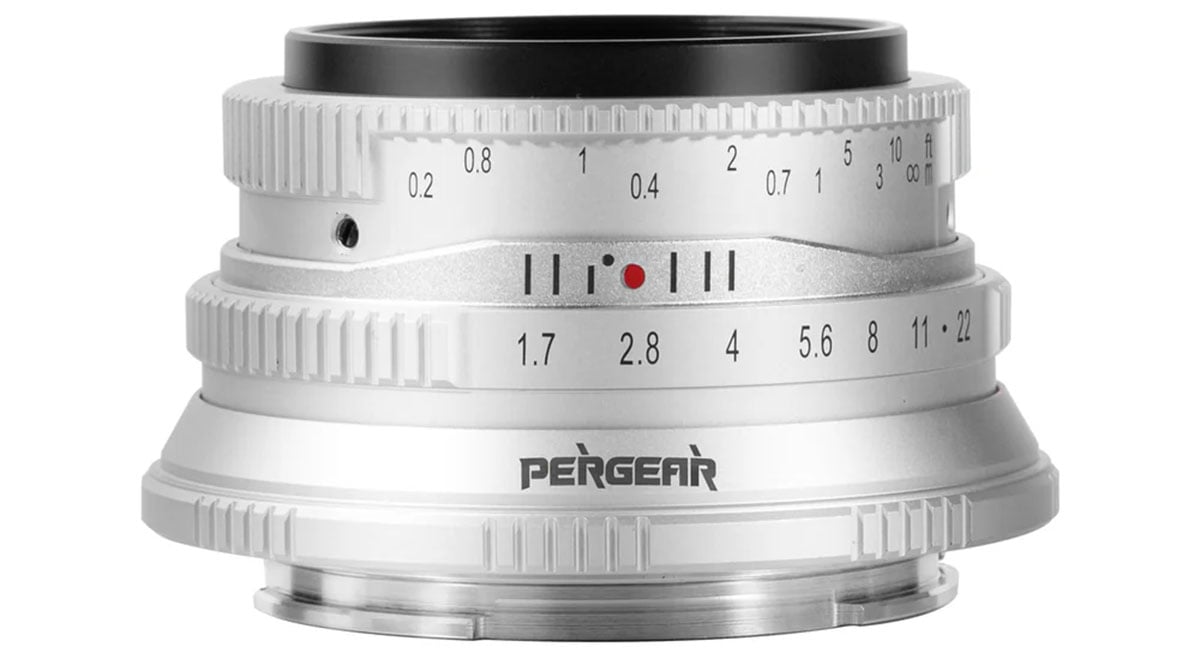 A close-up view of a pergear camera lens showing detailed focus and aperture settings marked in white on a silver body.