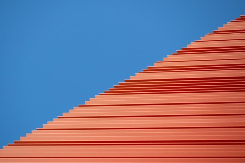 A vibrant image of a red, stepped structure against a clear blue sky, creating a visually striking geometric pattern.