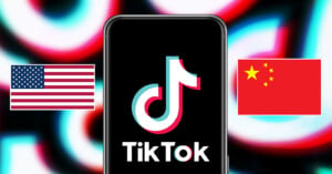 Smartphone displaying the tiktok logo centered on the screen, flanked by the us flag on the left and the chinese flag on the right, against a vibrant, blurred background.