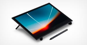 A digital drawing tablet featuring a sleek black design, resting at an angle with its stylus placed beside it on a white background. the tablet displays a vibrant abstract wallpaper.