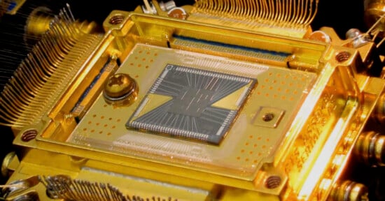 Close-up image of a quantum computer chip installed in a gold casing with visible intricate wiring and cooling mechanisms, highlighting advanced technology components.
