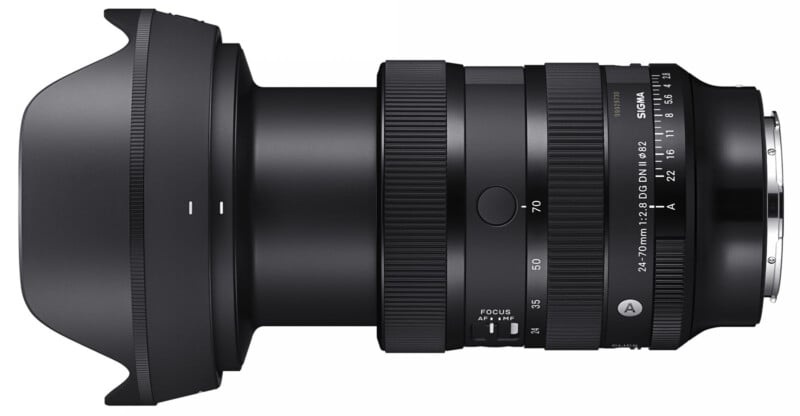 A black Sigma 24-70mm f/2.8 DG DN zoom lens is shown horizontally with the lens hood attached. The lens features various controls and markings, including a zoom ring, a focus ring, and a focus mode switch. The lens mount is visible on the right side.