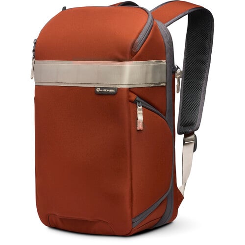 Un elegante bolso marrón con una correa plateada reflectante, asa resistente y correas ajustables se alza sobre un fondo liso.