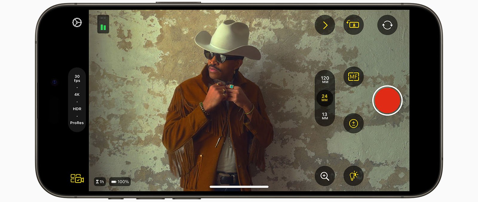 A smartphone screen displays a camera interface focused on a stylish man wearing a cowboy hat and leather jacket, lighting a cigarette. various camera settings are visible on the screen.