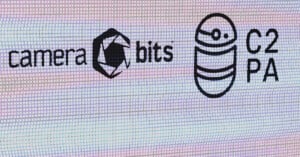 A digital screen displays logos, including the Camera Bits logo with a stylized camera aperture icon, and the C2PA logo featuring a circular design with horizontal lines and a dot. The words "camera bits" and "C2PA" are written next to their respective logos.