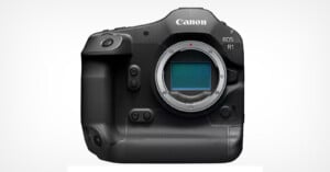 A high-resolution image of the Canon EOS R1 camera, showcasing its black body with the lens mount exposed. The camera features a textured grip, various buttons, and dials. The Canon logo and "EOS R1" are visible on the top right front of the camera. The background is white.
