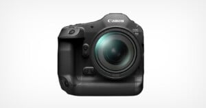 A Canon EOS R1 camera is shown from the front against a plain white background. The camera has a large lens and a textured grip on the left side, with various buttons and controls visible on its body.