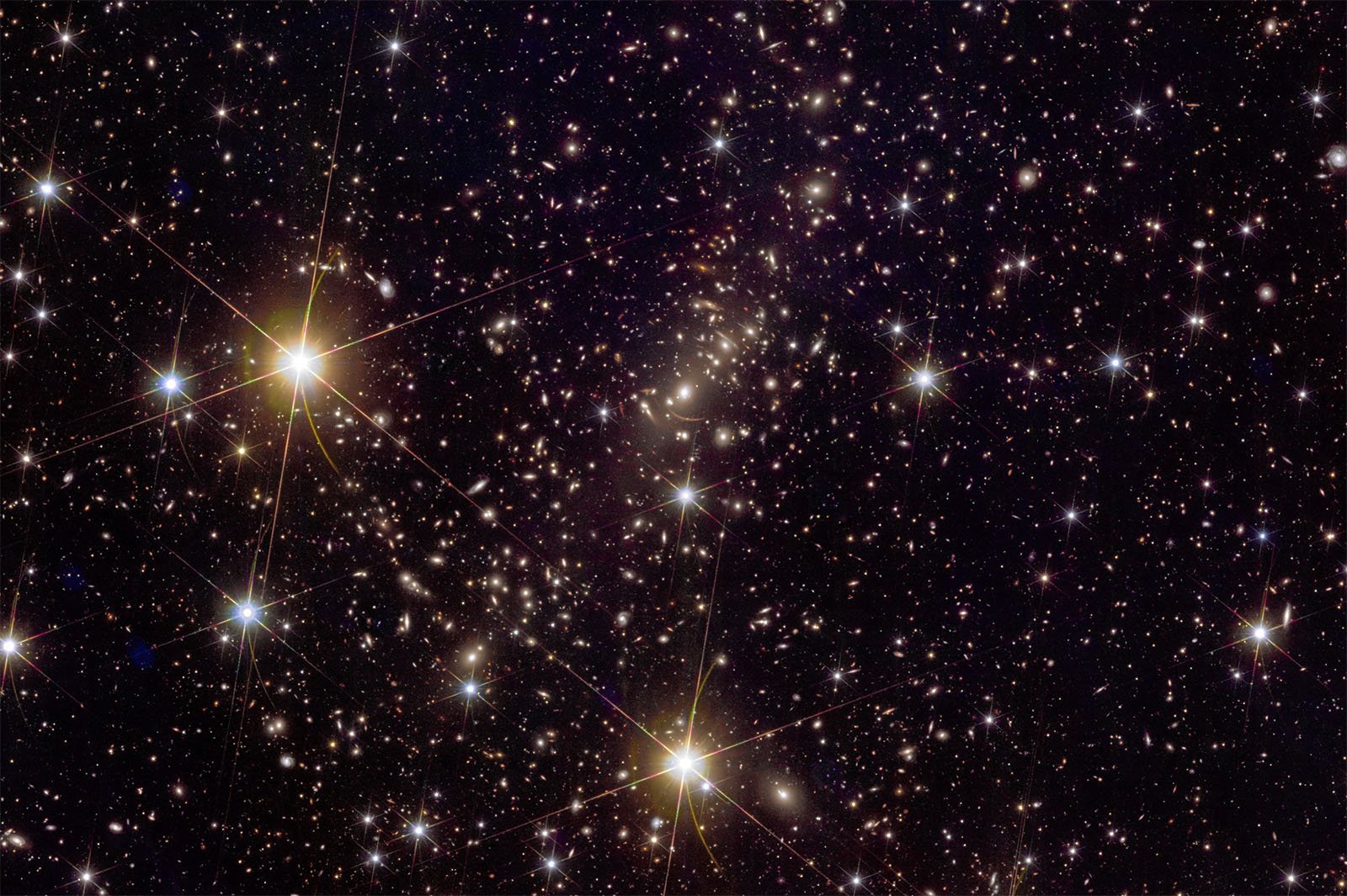 Image of a star-filled sky with countless bright stars and distant galaxies. Three large, bright stars in the foreground are prominently visible, creating a striking contrast with the myriad of smaller stars scattered throughout the dark expanse of space.