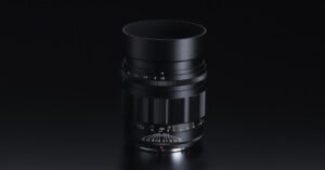 Black camera lens isolated on a dark background with visible focus scale and aperture settings.