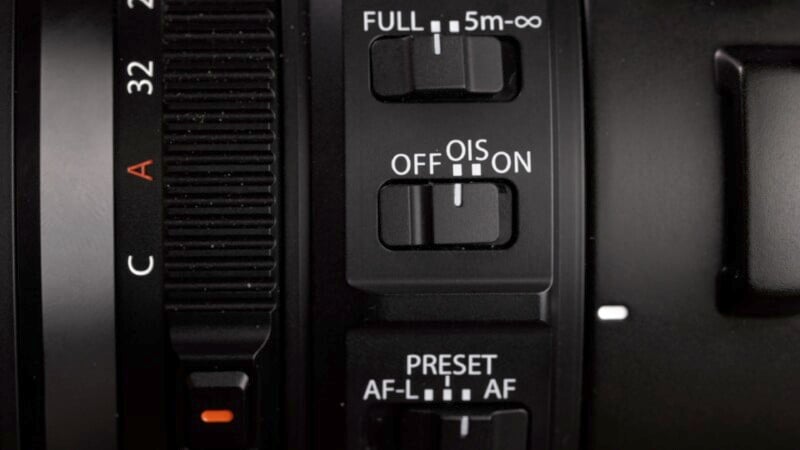 Close-up of the side controls on a camera lens. The buttons and switches include settings for 'FULL/5m-∞', 'OFF/OIS/ON', 'PRESET/AF-L/AF', and a red dot for alignment. The textured focus ring and a segment of the lens markings are also visible.