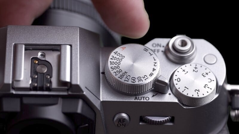 Close-up of a camera focusing on the mode dial and shutter speed controls, highlighting detailed engravings against a dark background.
