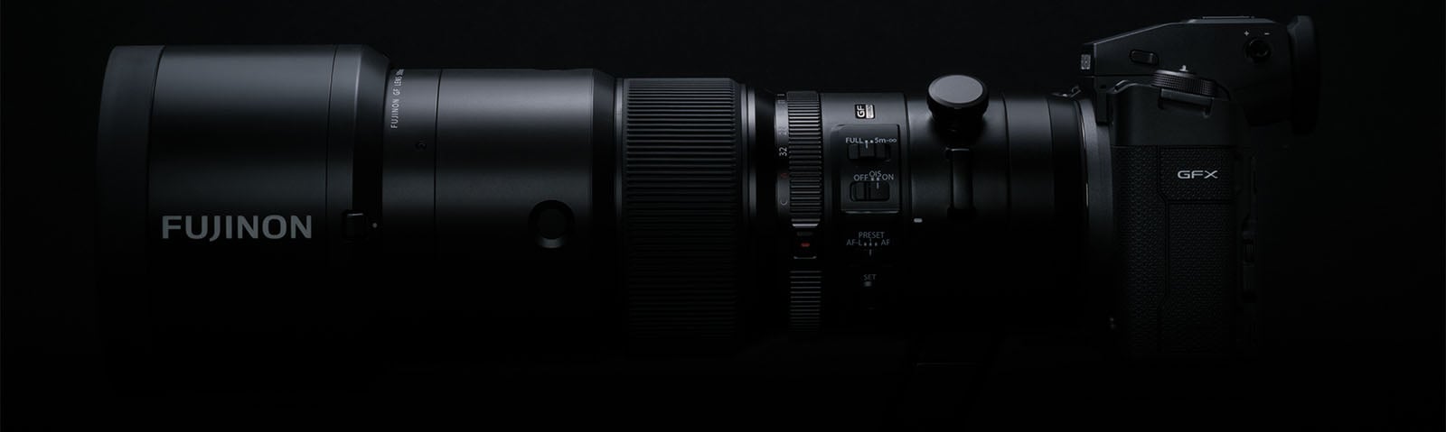 A close-up side view of a Fujifilm GFX camera equipped with a large Fujinon lens. The camera and lens are set against a black background, highlighting the details and controls on the lens and body. The image emphasizes the professional and sleek design of the equipment.