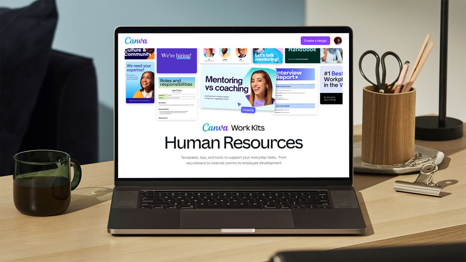 A laptop on a desk displays a Canva webpage for Human Resources work kits including templates, tips, and resources for employee development. The desk also has a coffee cup, plant, and some office supplies. The screen shows various HR themes like mentoring, coaching, and hiring.